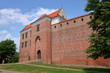 Widok zamku w Łęczycy, województwo łódzkie, Polska, budowla odrestaurowana, w otoczeniu zieleni, błękitne niebo z malowniczmy białymi chmurami