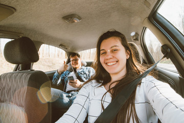 Wall Mural - woman driving a car. man sitting at backseats as passenger