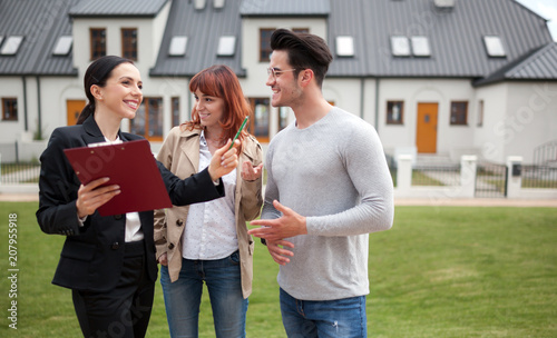 Fotografía Young couple with real estate agent visiting house for sale in residential area