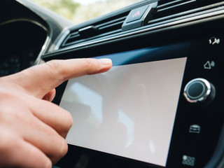 Woman pressing button on the white empty main screen in modern car dashboard driving on holiday highway