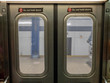 Windows of a moving subway train looking out into station platform upon departure