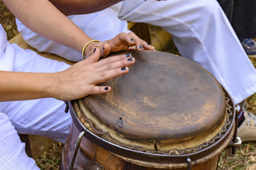 Young woman percussionist hands playing a drum called atabaque during brazilian folk music performance