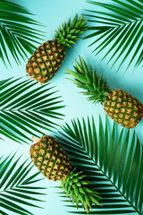  Pineapples and tropical palm leaves on pastel turquoise background. Summer concept. Creative flat alay with copy space. Top view