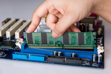 technician installing ram stick (random access memory) to socket on motherboard