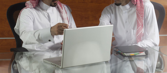 two saudi businessmen meeting, working on a laptop