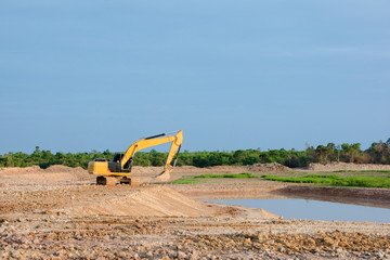 Wall Mural - Yellow excavator machine working earth moving works riverside at construction site