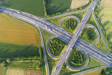 Cloverleaf Interchange Seen From Above. Aerial View Of Highway Road Junction In The Countryside With Trees And Cultivated Fields. Bird's Eye View.
