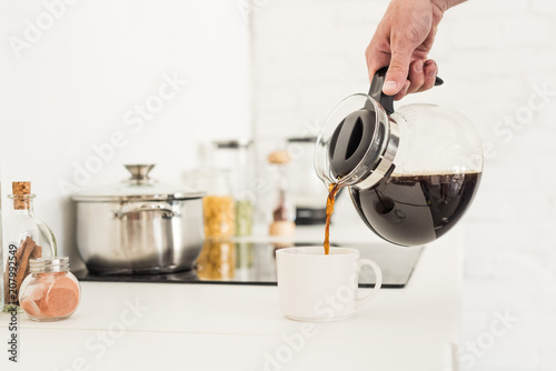 Cuadros en Lienzo cropped image of man pouring coffee into cup from coffee maker at kitchen