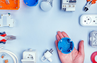 Wall Mural - Male hand with blue electricity box and Different electrical tools with text place. Top view, copy space.