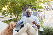 © Trinette Reed/Stocksy - Portrait of African American Senior man reading the newspaper on his patio outside with his dog