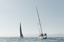 Two Sailboats With Black And White Sails Out On The Ocean In Yacht Race