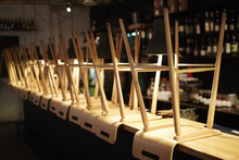 Wooden Stools Stacked Upside Down On Bar Counter At Night