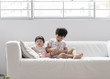 © Alita Ong/Stocksy - Brother and sister sitting on a couch