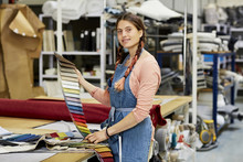 Confident Worker Holding Fabric Swatches In Sofa Workshop