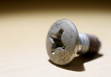 Fototapeta  - Macro view of a screw on beige surface at night.