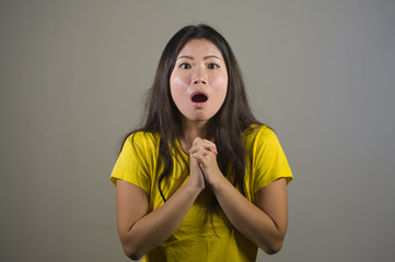 young pretty and amazed Asian Korean girl astonished and shocked in wonder and surprise gesturing with hands and wide open mouth isolated background