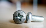 Fototapeta  - Two screws lying on table top.