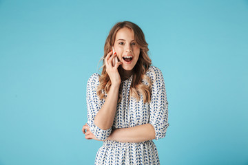 Poster - Surprised happy blonde woman in dress talking by smartphone