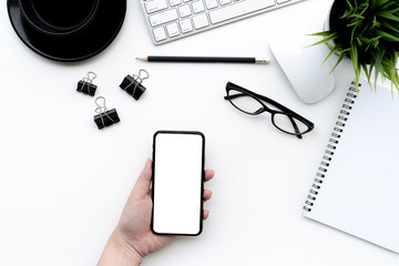 Wall Mural - Flat lay of top view Business woman use smartphone on modern white desk work table with computer laptop and stationary in home office includes copyspace for add text or graphic