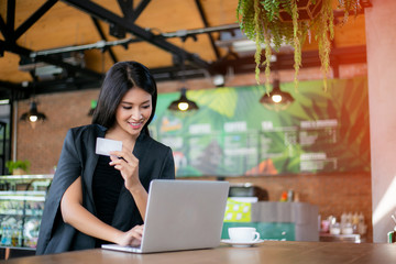 Young woman holding credit card and using laptop computer. Online shopping concept