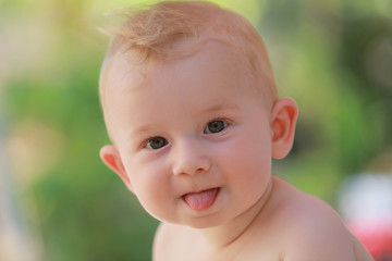 Petit bébé garçon tire la langue. Soleil, été, nature, jolie lumière