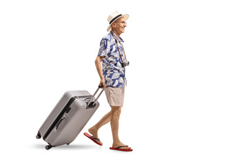 Wall Mural - Elderly tourist walking and dragging a suitcase