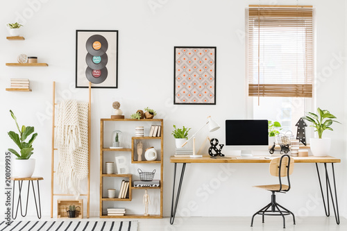 Fotografía Real photo of a workplace interior with a computer on a desk next to a chair and