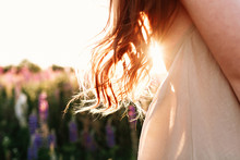 Close Up Of Beautiful Woman Lock Of Hair On Sunset Background In Flower Field. Selective Focus