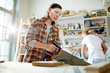 © pressmaster - Adult woman in safety goggles using saw to cut timber board while working in carpenter workshop