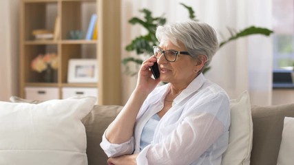 Wall Mural - technology, communication and people concept - happy senior woman calling on smartphone at home