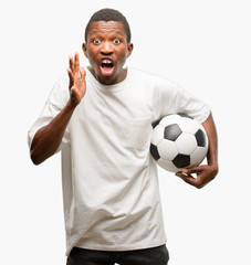 Poster - African black man holding soccer ball stressful keeping hands on head, terrified in panic, shouting