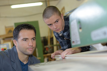 Wall Mural - Men aligning wood into machine