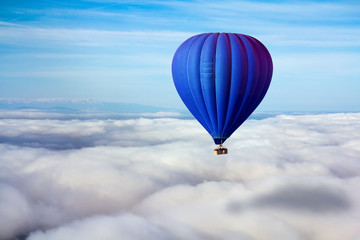 A lonely blue hot air balloon floats above the clouds. Concept leader, success, loneliness, victory