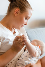 Caring Young Mother Breastfeeds Baby Girl At Home