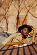 © Carlos David - Portrait of a woman in a shadowy park with hat writing by hand looking at camera