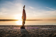 © Igor Kardasov - Silhouette woman on the beach at sunset doing yoga asana. Morning natural stretch warm-up training