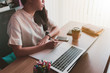 © bunditinay - Young woman working at a home office with a laptop on table and smartphone. Concept of female freelancer business.Vintage tone