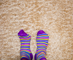 striped colored socks, legs on a warm mat