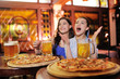 © Evgeniy Kalinovskiy - two young pretty girls eating pizza, drinking beer or a beer cocktail and watching football