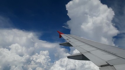 Wall Mural - 4K footage. traveling by air. aerial view through an airplane window. wing airplane between turn direction for landing time and beautiful white clouds in blue sky for travel background