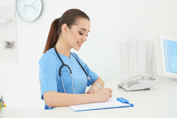 Wall Mural - Young female doctor working at reception desk in hospital