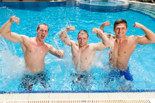 Sport, Health Lifestyle, Summer Concept. Three Strongly Built Men Are Standing In The Outdoor Swimming Pool And Posing As Athletes Or Wrestler Showing Their Great Muscles