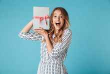 Shocked blonde woman in dress holding gift box