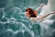 © Ulia Koltyrina - Underwater girl. Beautiful red-haired woman in a white dress, swimming under water.