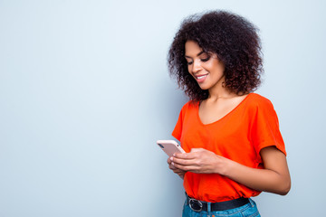 Portrait with copy-space of busy charming woman with modern hairdo in bright outfit holding smart phone in hands using wifi 5G internet checking email searching contact isolated on grey background