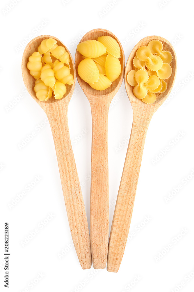 Wooden spoons with different types of pasta on white background
