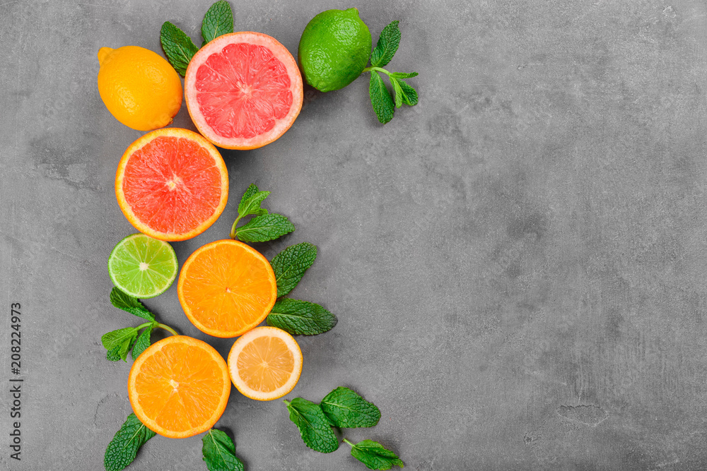 Ripe citrus fruits and mint on grey background