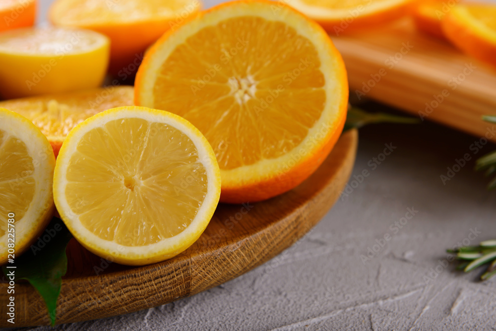 Wooden board with ripe citrus fruits on table