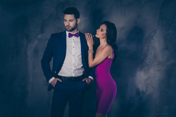 Side view portrait of charming slim pretty woman putting arms on shoulder of dreamy bearded man in blue tux holding two hands in pockets of pants  attractive spouses isolated on grey background