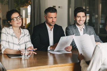 Poster - Business, career and placement concept - three executive directors or head managers sitting at table in office, and interviewing woman during meeting